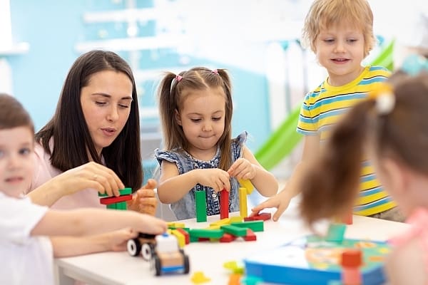 a group of kids building toys at play room together with a teacher - Toddler Toys a group of kids building toys at play room together with a teacher