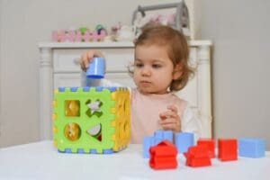 kid putting a piece of a puzzle in a puzzle box